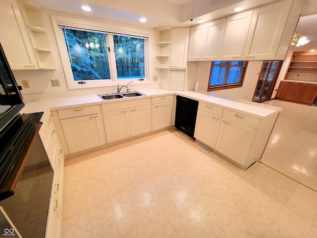 kitchen featuring black appliances, sink, kitchen peninsula, pendant lighting, and white cabinets