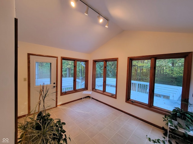 unfurnished sunroom with lofted ceiling, track lighting, and plenty of natural light