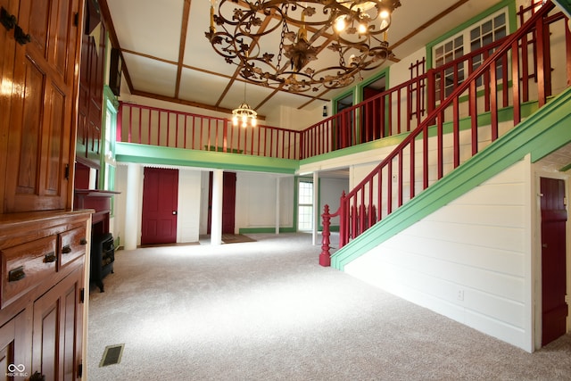 carpeted living room featuring a notable chandelier and a towering ceiling