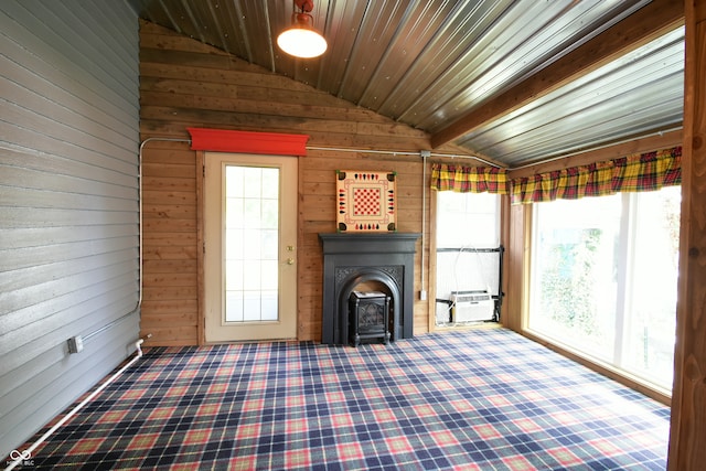 unfurnished living room with lofted ceiling with beams, wood ceiling, a wood stove, and wood walls