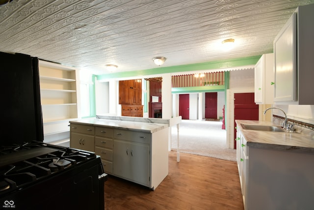 kitchen with hardwood / wood-style floors, sink, white cabinets, and black appliances