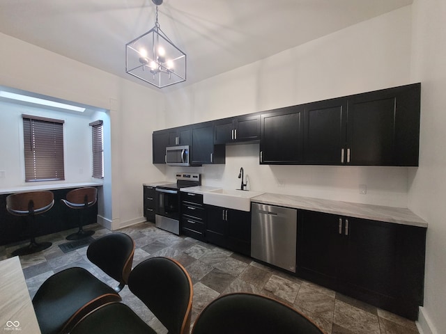 kitchen with light stone countertops, appliances with stainless steel finishes, sink, pendant lighting, and an inviting chandelier