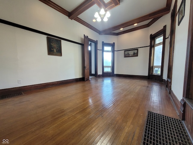 empty room featuring crown molding, dark hardwood / wood-style floors, beam ceiling, and a wealth of natural light