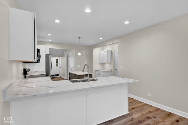 kitchen featuring light wood-type flooring, sink, kitchen peninsula, and white cabinets