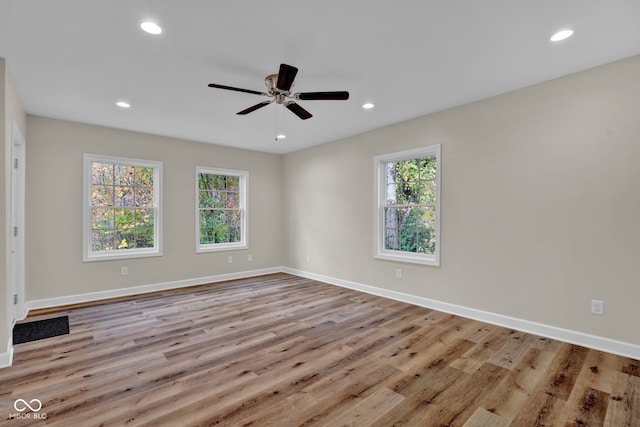 empty room featuring ceiling fan, a wealth of natural light, and light wood-type flooring