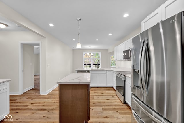 kitchen with appliances with stainless steel finishes, light stone counters, light wood-type flooring, and white cabinetry