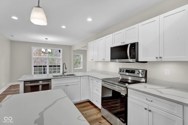 kitchen featuring appliances with stainless steel finishes, white cabinets, sink, and decorative light fixtures