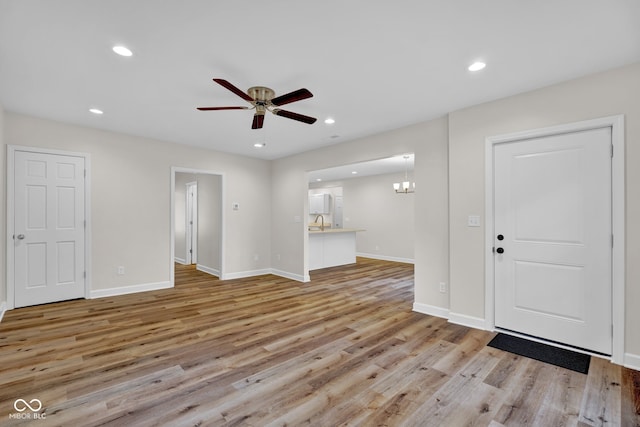 foyer entrance featuring light hardwood / wood-style floors and ceiling fan with notable chandelier