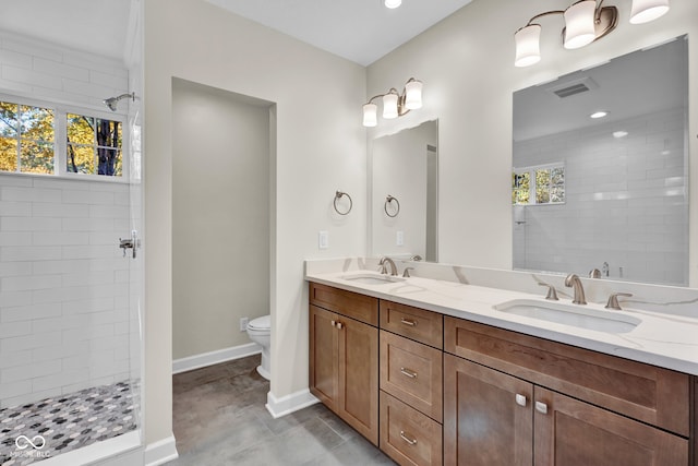 bathroom featuring vanity, a tile shower, toilet, and a healthy amount of sunlight