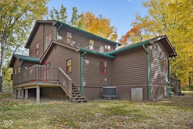 rear view of house featuring a deck, cooling unit, and a lawn