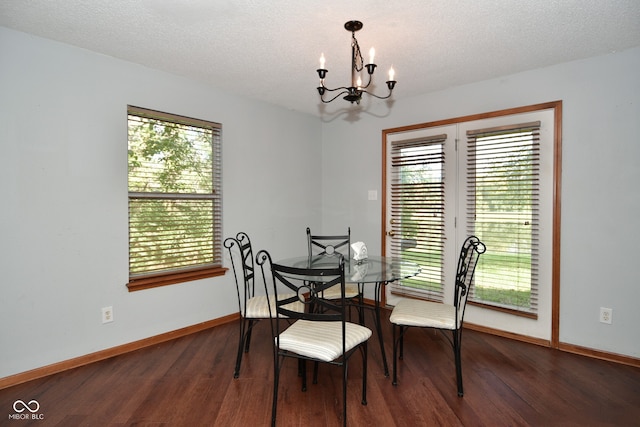 dining area featuring an inviting chandelier, a textured ceiling, and dark wood-type flooring