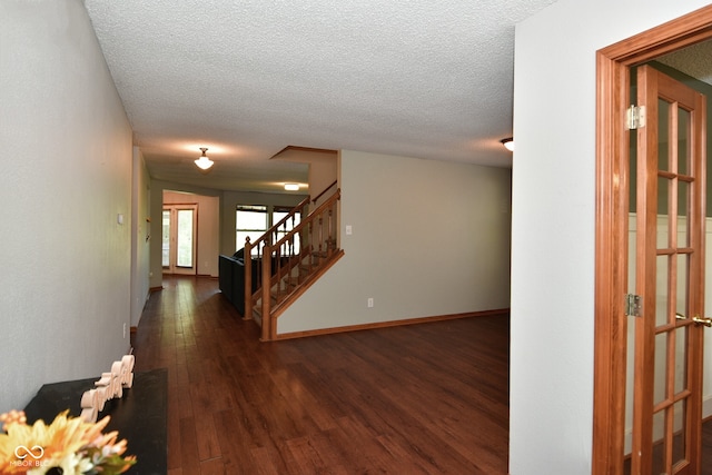 corridor with a textured ceiling and dark wood-type flooring