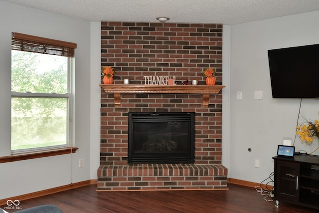 unfurnished living room with a textured ceiling, a brick fireplace, and dark hardwood / wood-style floors