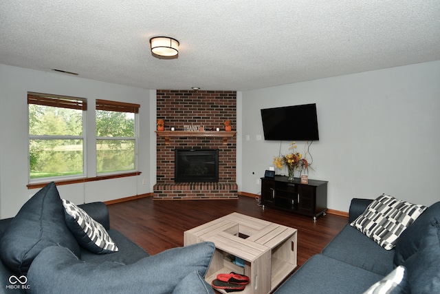 living room with a textured ceiling, a brick fireplace, and dark hardwood / wood-style floors