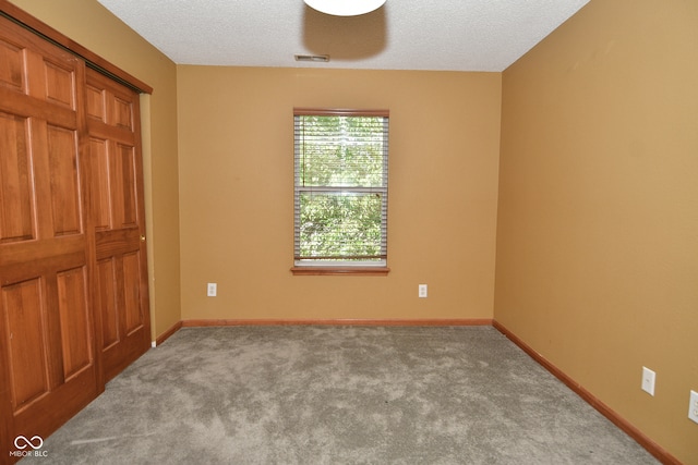 carpeted spare room with a textured ceiling