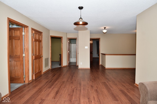 spare room featuring a textured ceiling and dark wood-type flooring