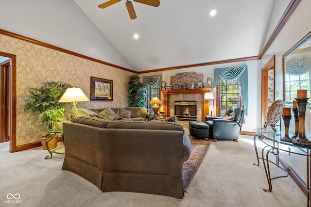 carpeted living room featuring a tiled fireplace, high vaulted ceiling, ornamental molding, and ceiling fan