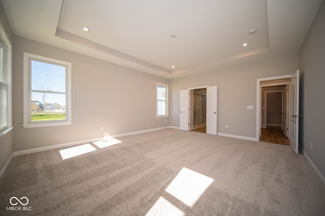 unfurnished bedroom with carpet floors and a tray ceiling