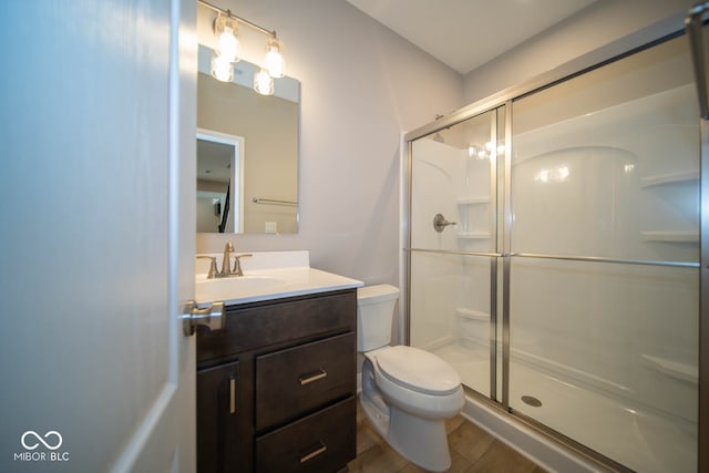 bathroom with vanity, hardwood / wood-style flooring, toilet, and a shower with shower door