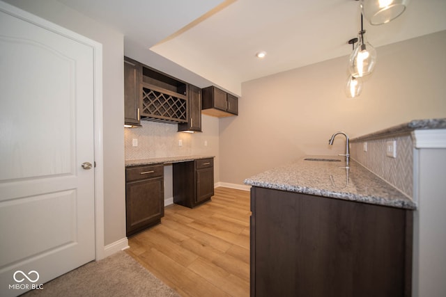 kitchen with dark brown cabinetry, light stone countertops, sink, light hardwood / wood-style flooring, and decorative backsplash