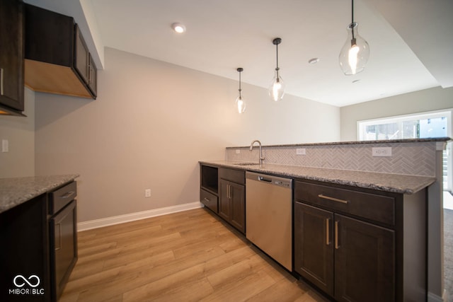 kitchen with light stone countertops, light wood-type flooring, sink, decorative light fixtures, and dishwasher