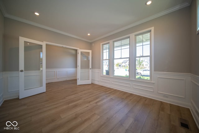 unfurnished room featuring french doors, ornamental molding, and wood-type flooring