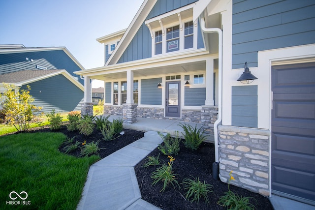 property entrance featuring a lawn, a porch, and a garage