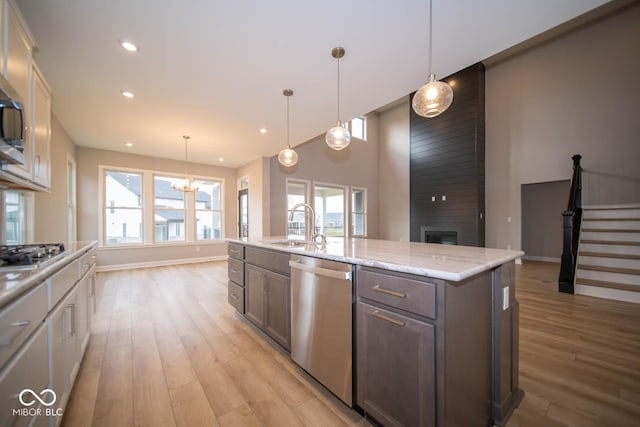 kitchen with pendant lighting, a kitchen island with sink, sink, a fireplace, and stainless steel appliances