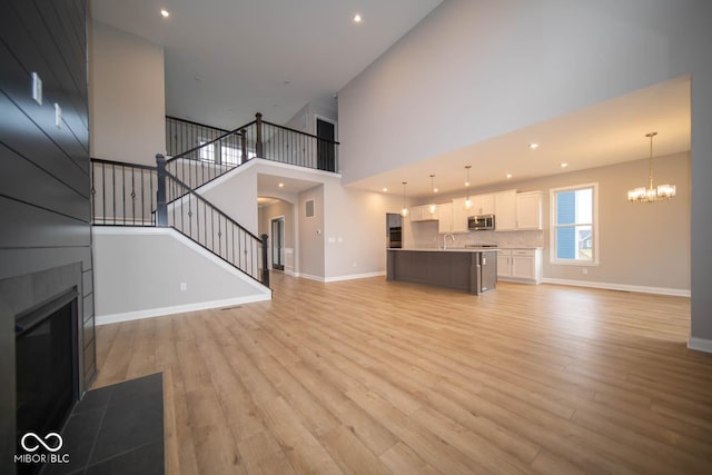 unfurnished living room with a high ceiling, light hardwood / wood-style floors, and a notable chandelier