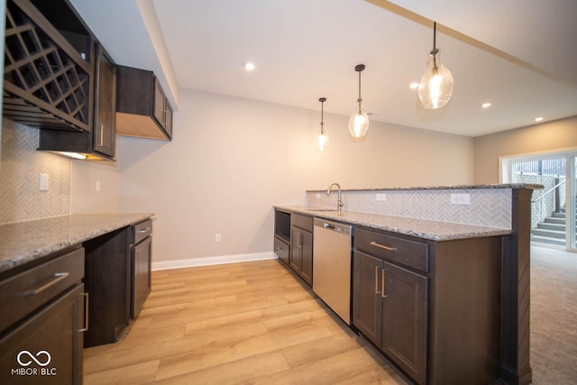 kitchen featuring light stone counters, dishwasher, decorative light fixtures, and sink