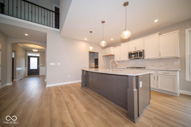 kitchen featuring sink, hanging light fixtures, a center island with sink, white cabinets, and appliances with stainless steel finishes