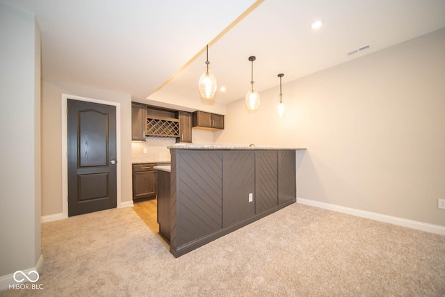 kitchen with kitchen peninsula, light carpet, and decorative light fixtures