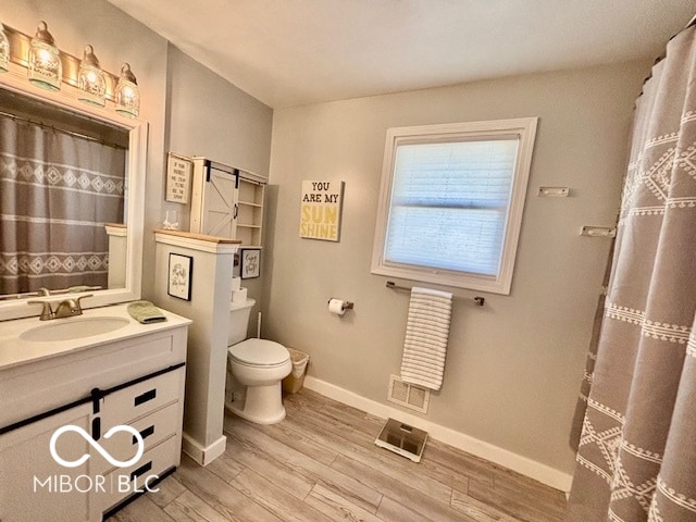 bathroom with toilet, hardwood / wood-style floors, and vanity