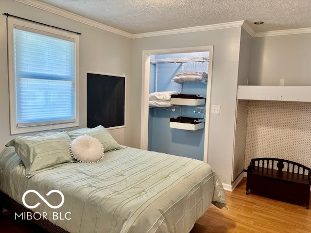 bedroom featuring crown molding, a textured ceiling, and hardwood / wood-style flooring