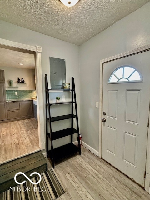 foyer featuring light hardwood / wood-style flooring, a textured ceiling, and electric panel