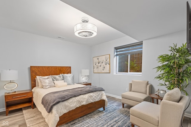 bedroom featuring visible vents, light wood-style flooring, baseboards, and a notable chandelier