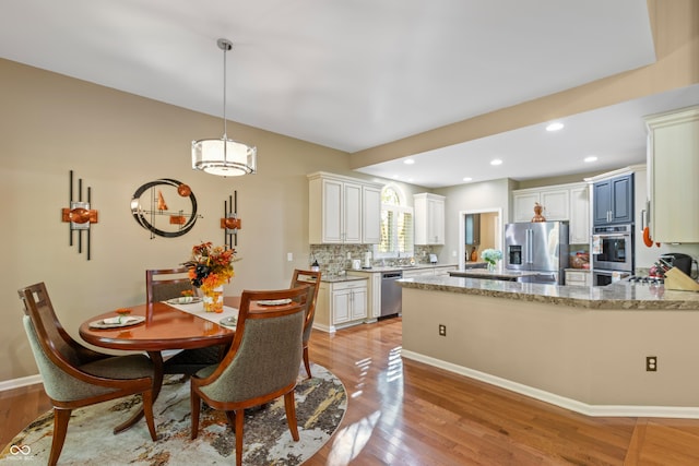 dining room with recessed lighting, light wood finished floors, baseboards, and an inviting chandelier