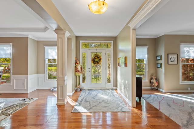 entrance foyer featuring a wealth of natural light, decorative columns, crown molding, and light hardwood / wood-style floors