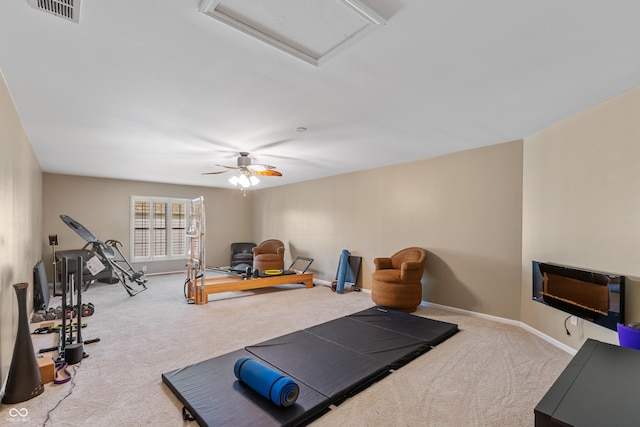exercise room with carpet, visible vents, a ceiling fan, baseboards, and attic access