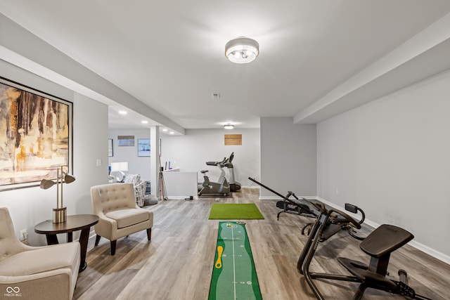 exercise room with baseboards, light wood finished floors, and recessed lighting