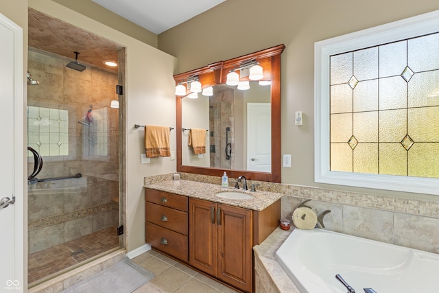 full bath with a stall shower, plenty of natural light, tile patterned flooring, a garden tub, and vanity