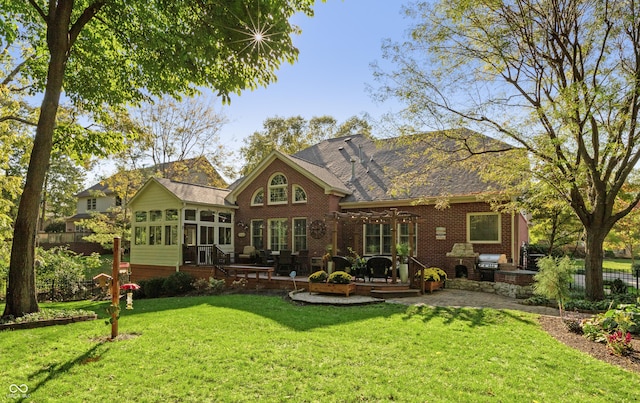 back of house with brick siding, a lawn, a wooden deck, a sunroom, and roof with shingles