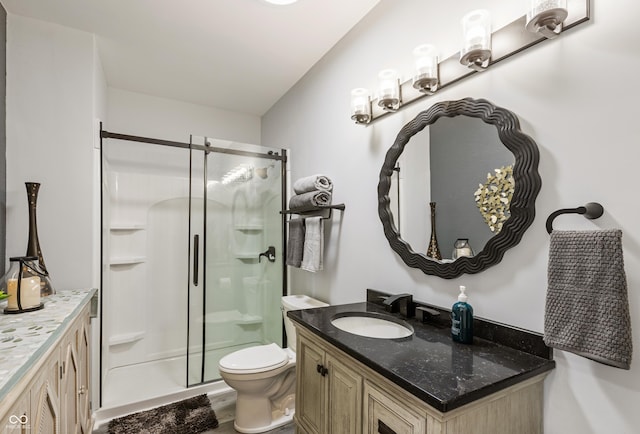 bathroom featuring toilet, vanity, and a stall shower