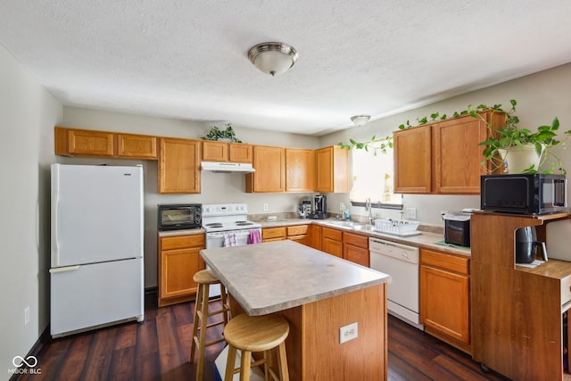 kitchen with sink, a center island, a textured ceiling, dark hardwood / wood-style flooring, and white appliances