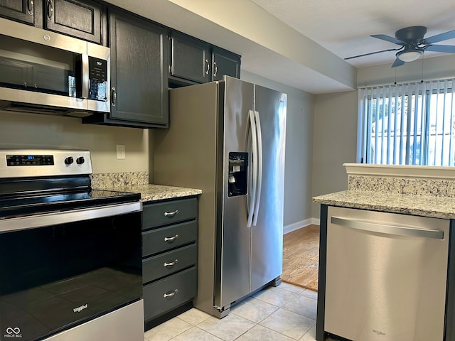 kitchen featuring appliances with stainless steel finishes, light hardwood / wood-style floors, light stone counters, and ceiling fan