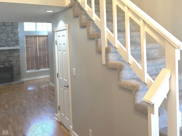 stairs with a fireplace and wood-type flooring