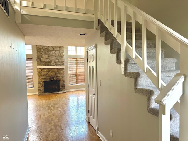 stairway featuring hardwood / wood-style floors, a towering ceiling, and a fireplace