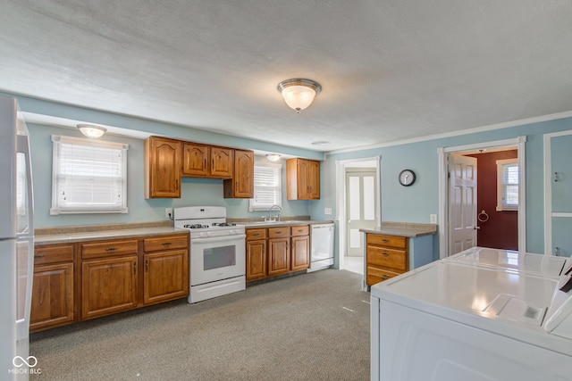 kitchen with light carpet, a textured ceiling, washing machine and dryer, sink, and white appliances