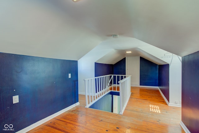 additional living space with vaulted ceiling and wood-type flooring