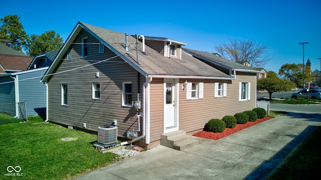 rear view of property featuring a yard and central AC unit